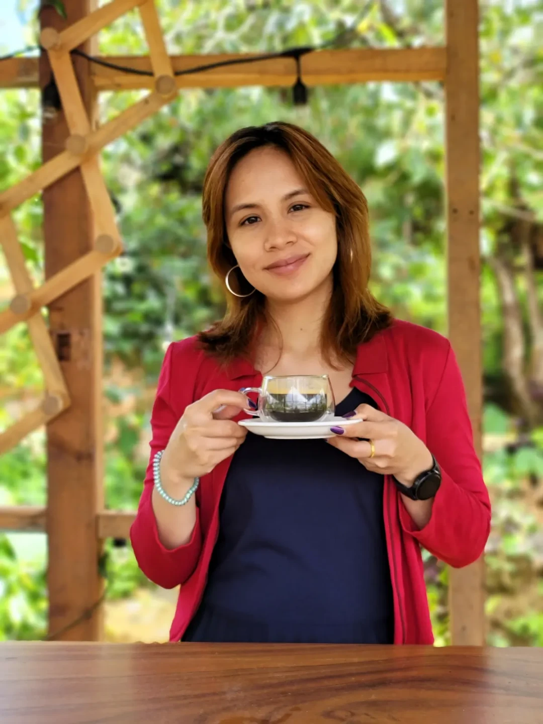 Elle smiling and holding a glass teacup and saucer.