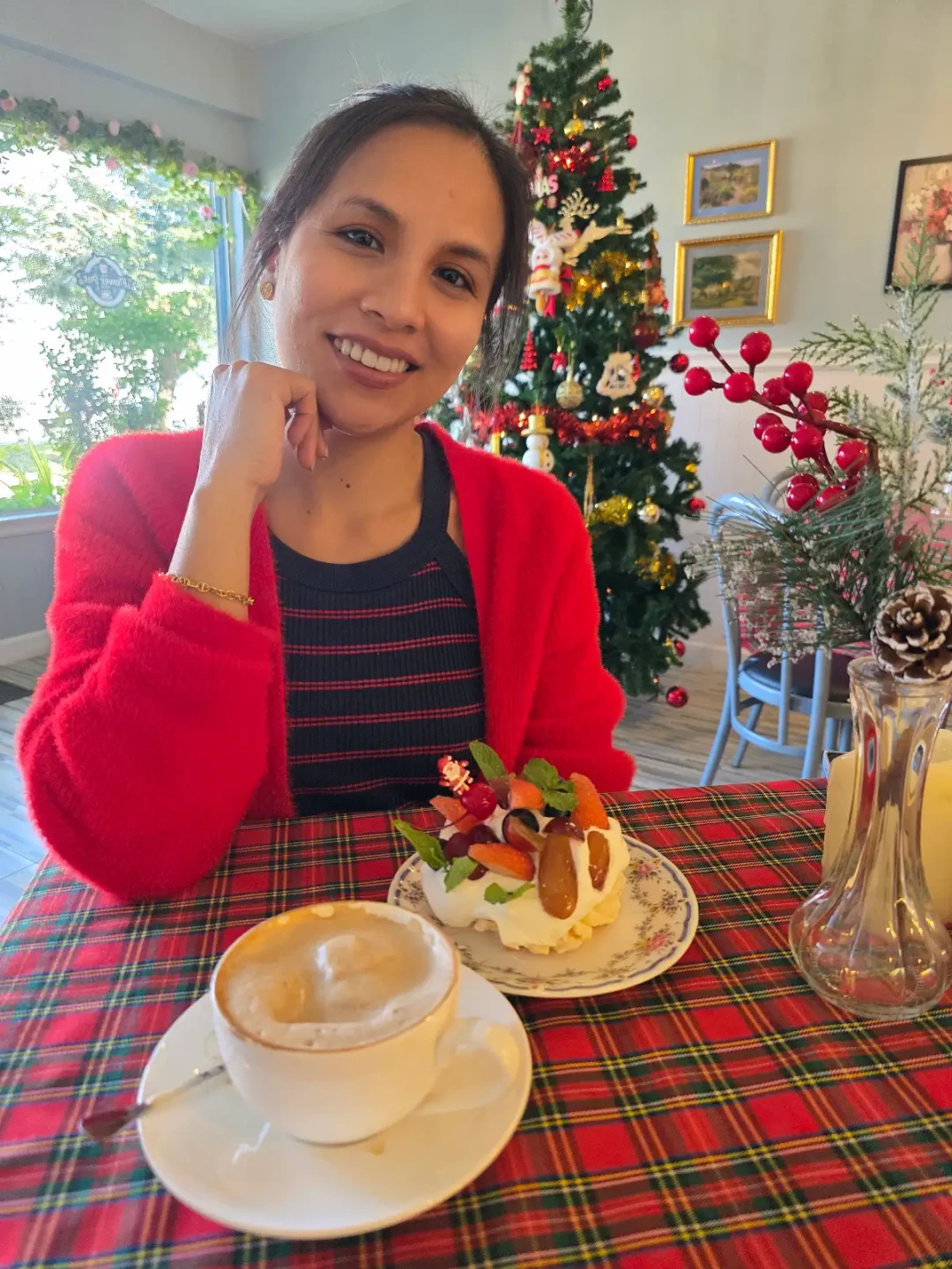Elle smiling at a Christmas table with pavlova and cappuccino.