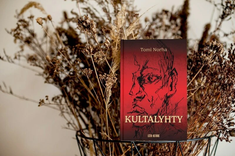 Kultalyhty-kirja kuivattujen kukkien keskellä